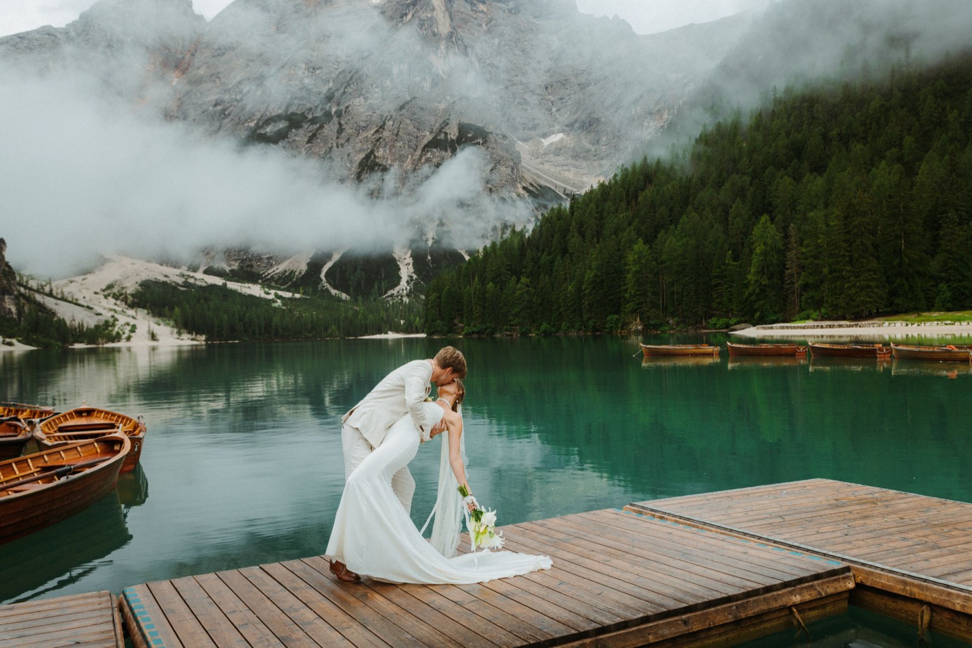 A couple on a jetty by a misty alpine lake