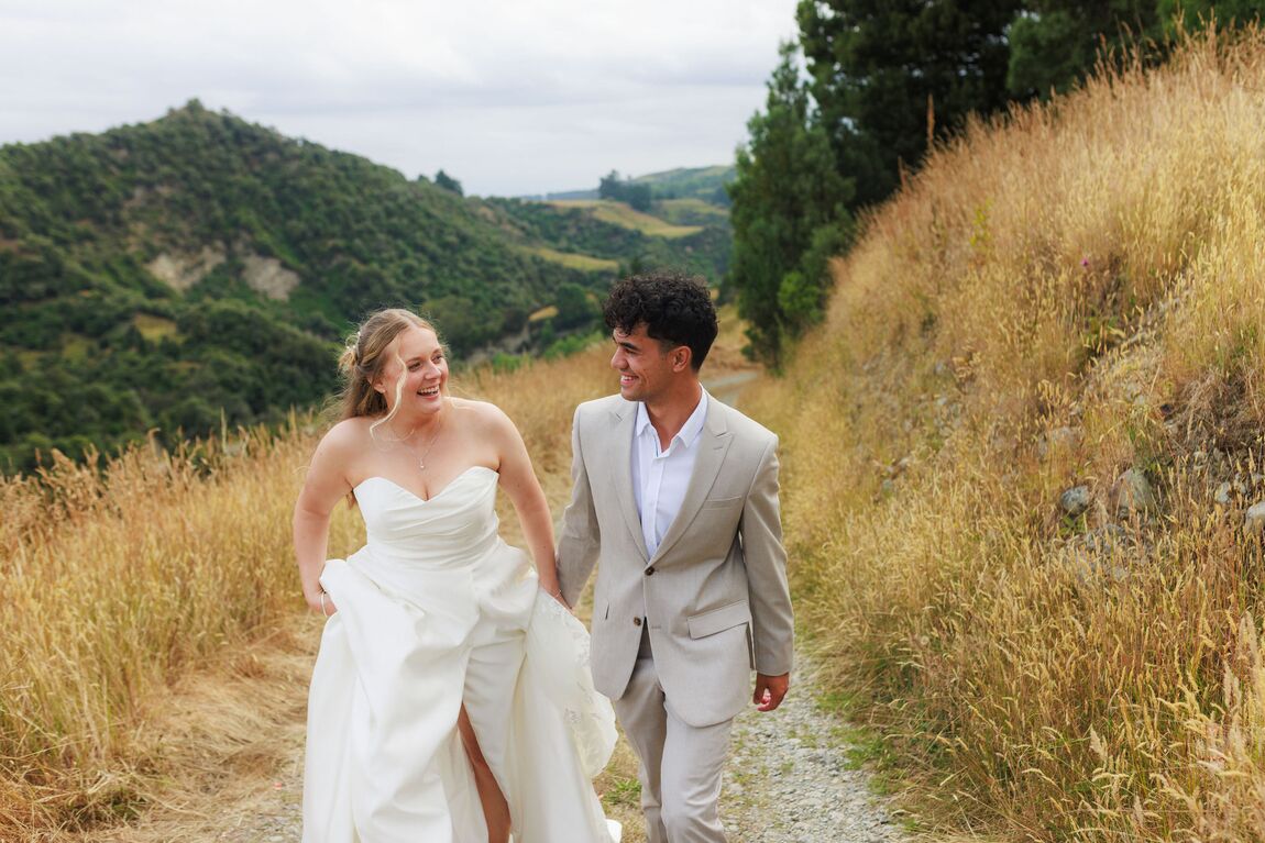 Couple walking down a grassy hillside at their wedding